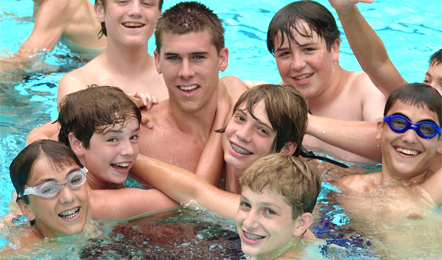 A camp counselor and campers splashing in the pool
